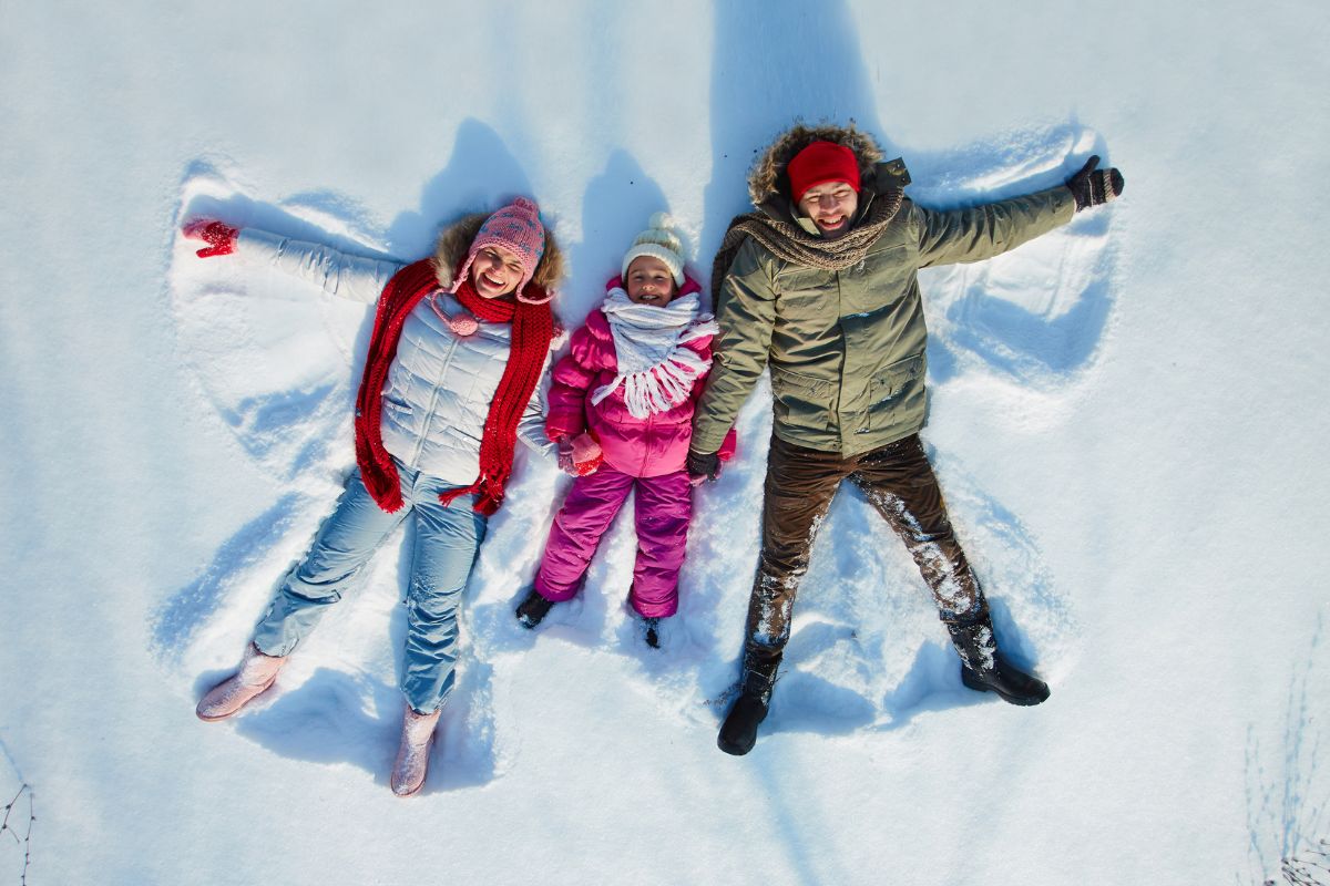 family making snow angels canva